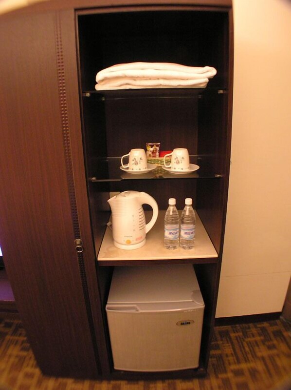 A hotel minibar with a coffee maker, two bottles of water, and a tea set. - Moon Villa (Zhongpu)