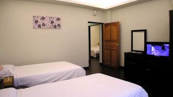 A hotel room with two single beds, a television, a wooden door, and a small painting on the wall.
