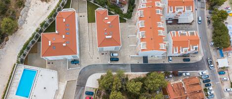 Vista aérea de una zona residencial con varios edificios, una piscina y una carretera.