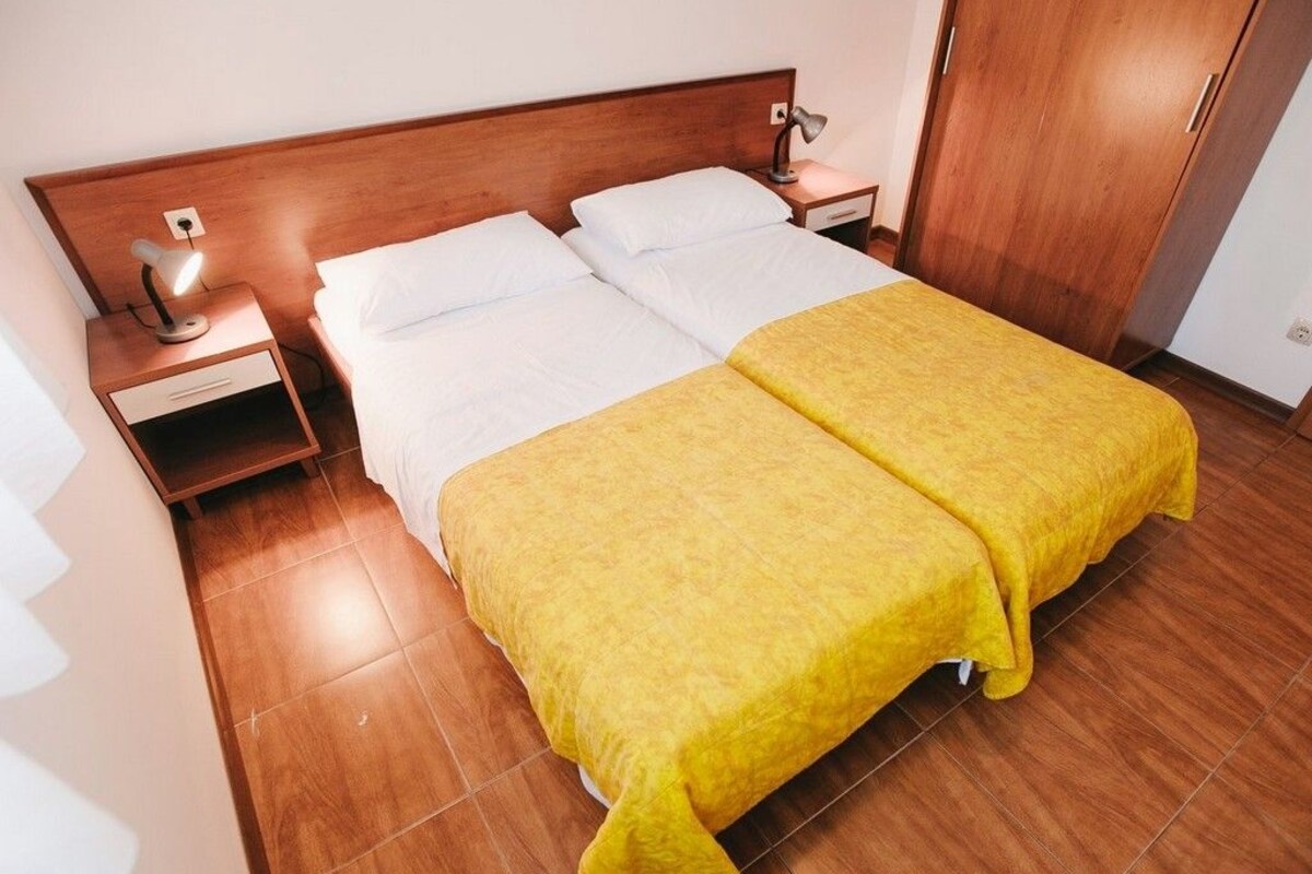 Una cama doble con cabecera de madera, dos mesitas de noche y un tocador.