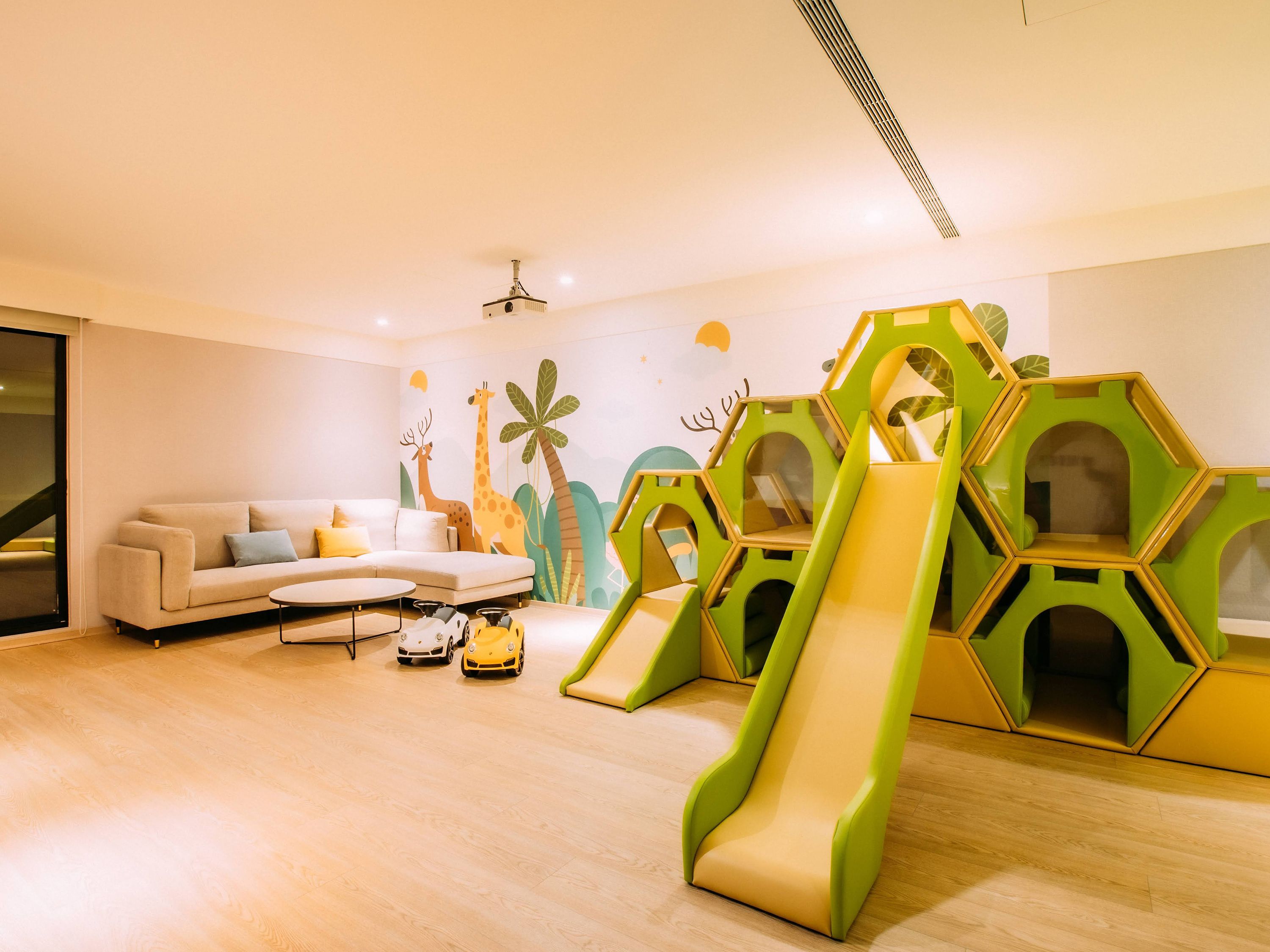 A modern children's play area with a slide, hexagonal play structures, and a sofa.
