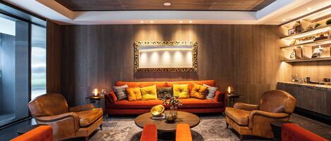 A modern living room with a sofa, two armchairs, a coffee table, and a fireplace.