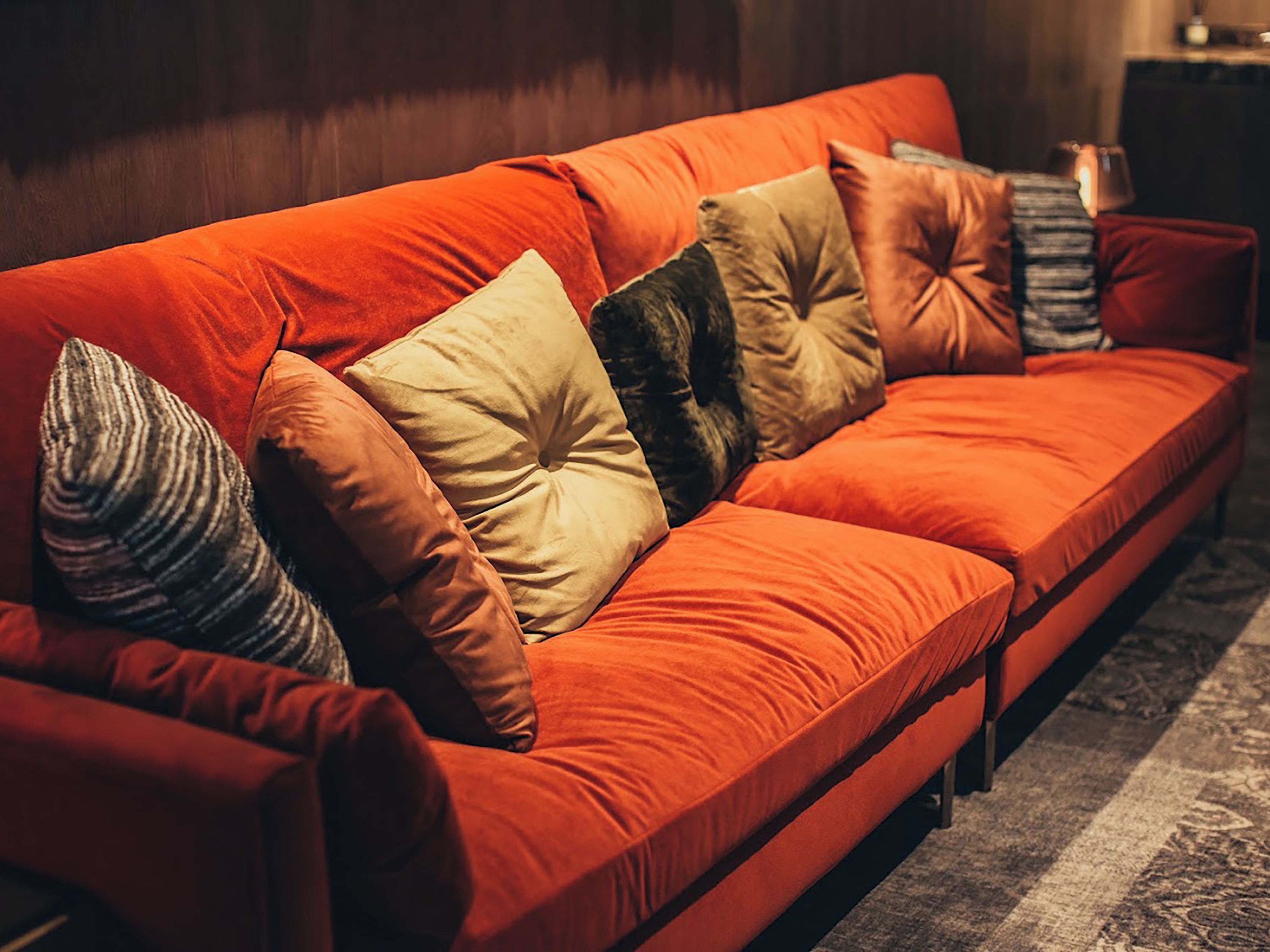 A sofa with multiple cushions in a room with a patterned rug.