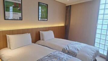 A hotel room with two beds, a large window, and two posters on the wall.
