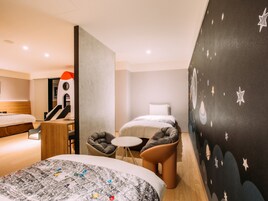 Habitación de hotel con dos camas, un escritorio, una silla y una pared con diseño de estrellas.