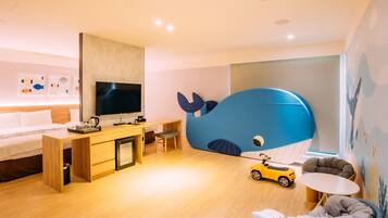 Quarto moderno com cama, escrivaninha, televisão e uma grande cabeceira com tema de baleia.
