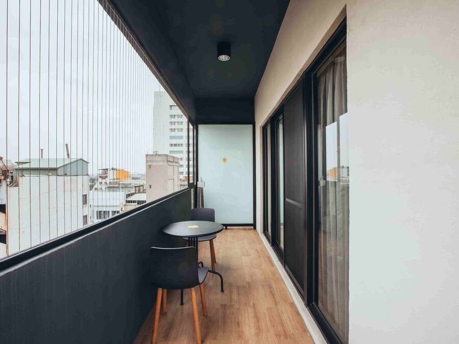 A balcony with a view of buildings, a table, two chairs, and a door.