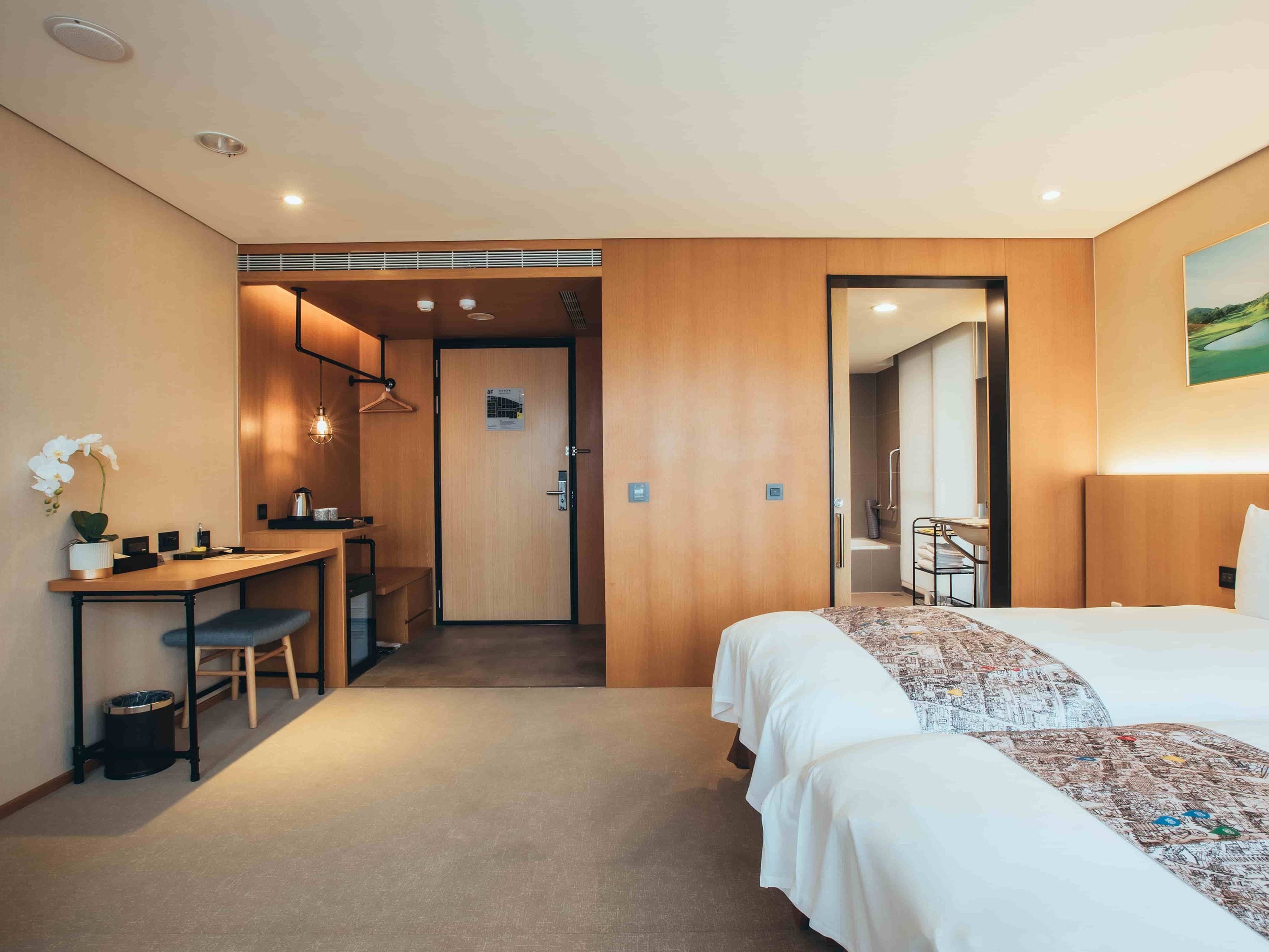 A hotel room with a bed, a desk, and a shower area.