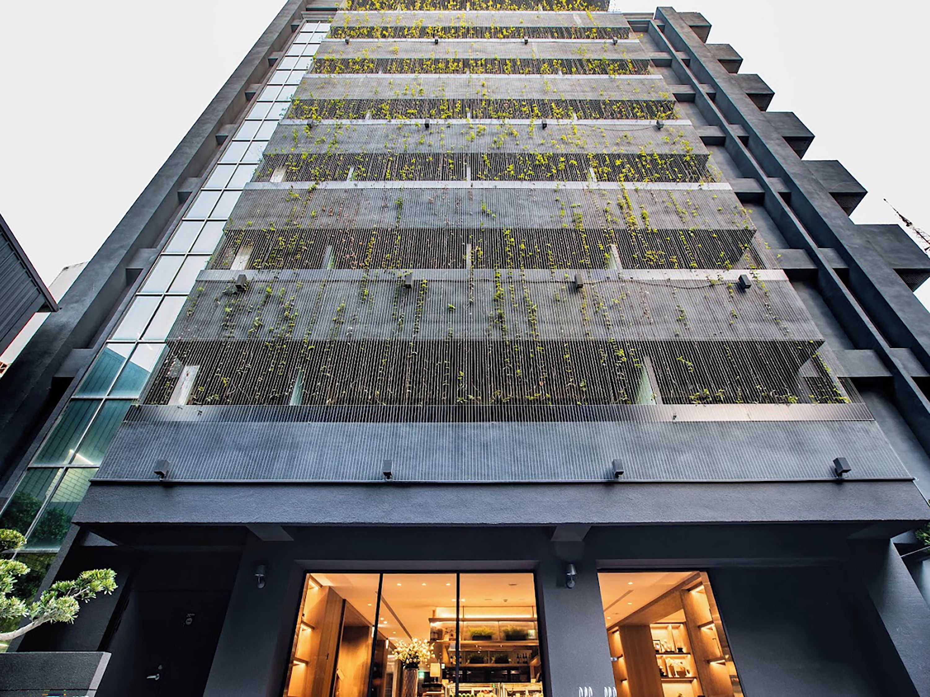 A modern building with a glass facade and a rooftop garden.