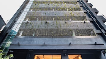 A modern building with a glass facade and a rooftop garden.