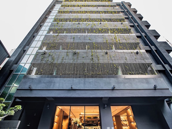 Un edificio moderno con fachada de vidrio y jardín en la azotea.
