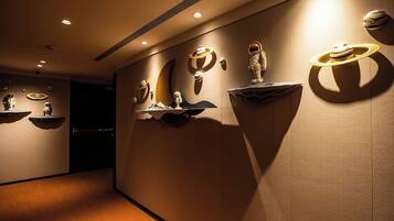 A hallway with wall-mounted sculptures and recessed lighting.