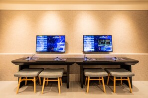 A conference room with two large monitors displaying the same content, a long table, and four grey cushioned stools. - CHECK inn SELECT Chiayi RenAi (Chiayi City)