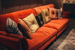 Ein rotes Sofa mit mehreren Kissen in einem Raum mit einem gemusterten Teppich.