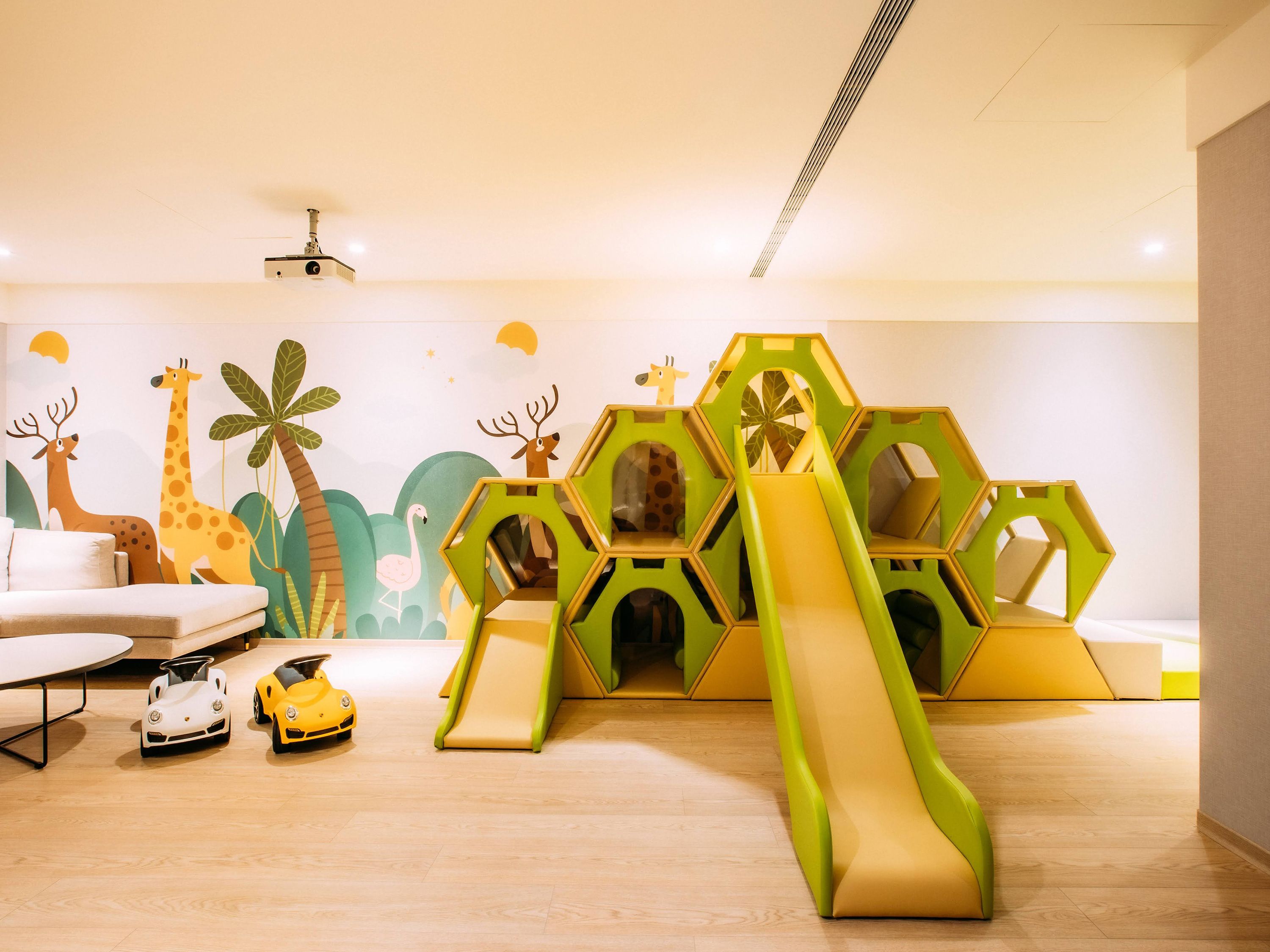 Un área de juegos con un tobogán, estructuras de juego hexagonales y coches de juguete.