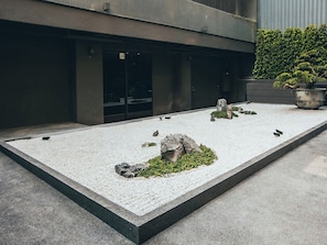 Un patio con suelo de grava, una formación rocosa y una planta en maceta.