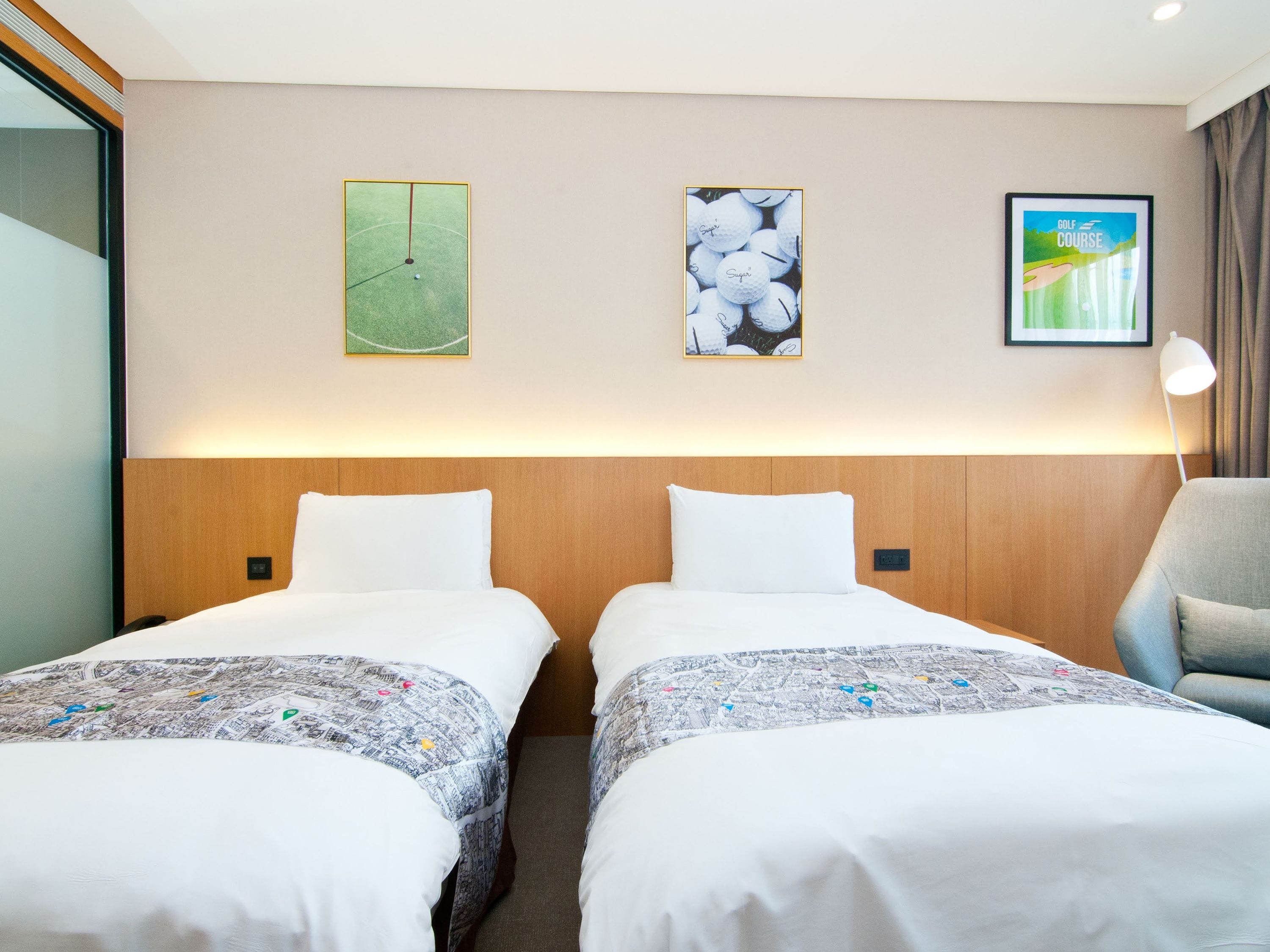 Habitación de hotel con dos camas, cabecera de madera y un cuadro con temática de golf.