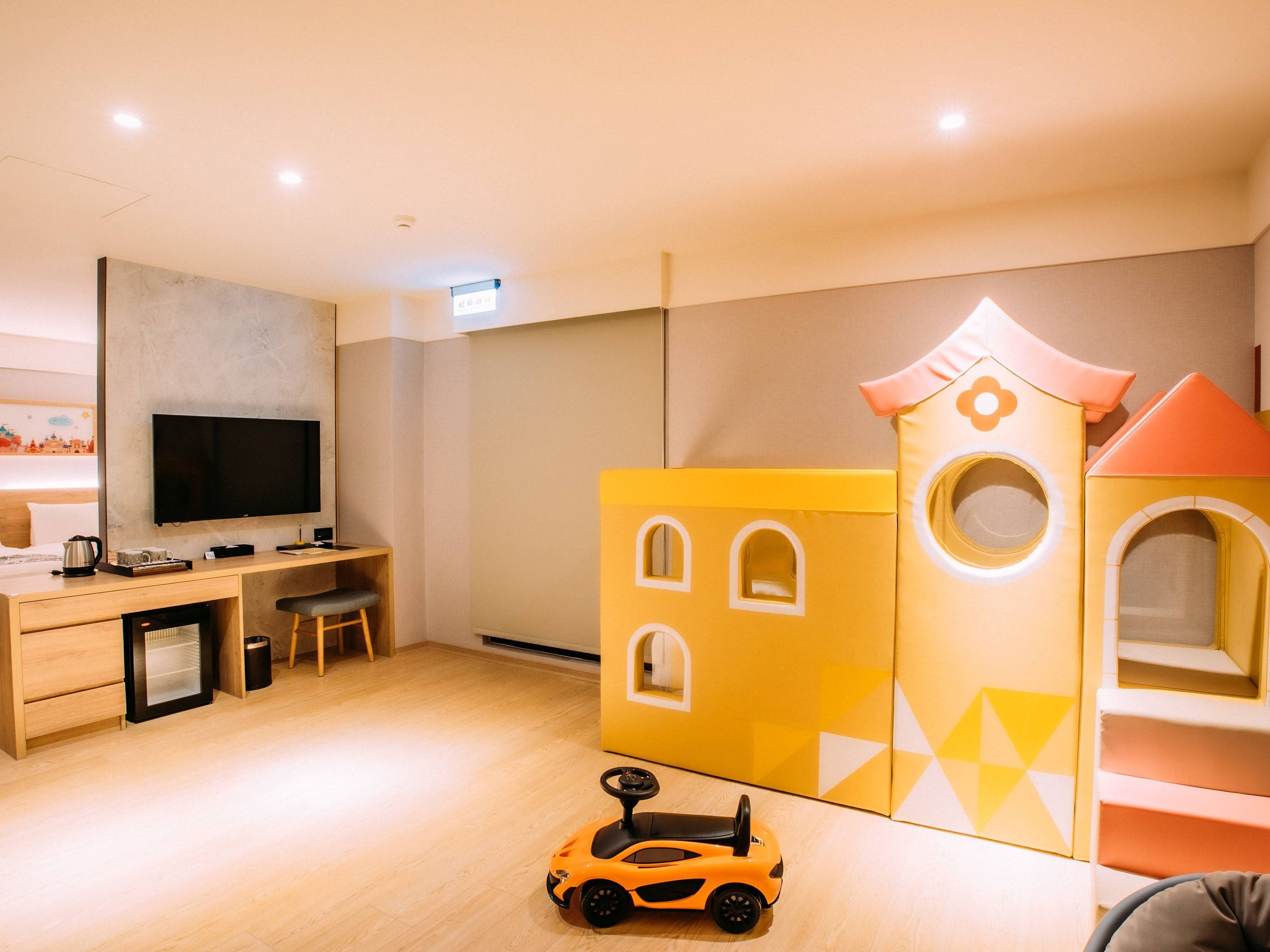 Zona de juegos para niños con una casita y un coche de juguete.