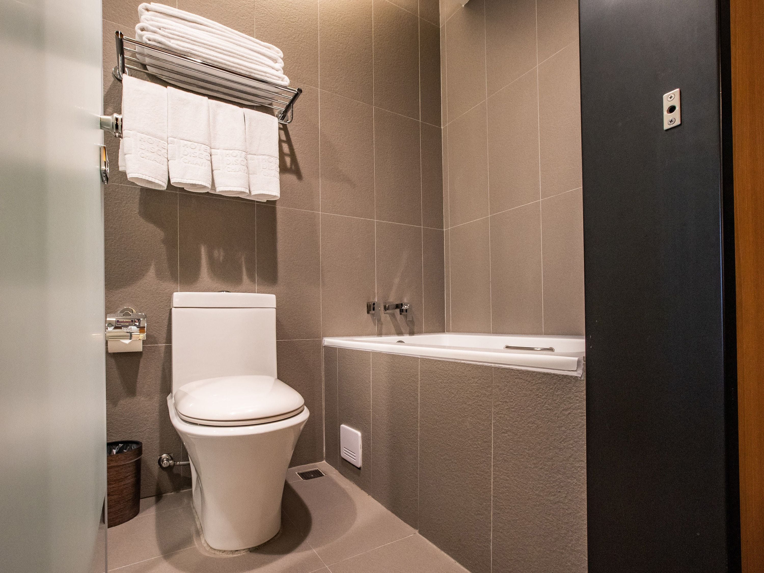 Une salle de bain moderne équipée de toilettes, d’un porte-serviettes et d’une baignoire.