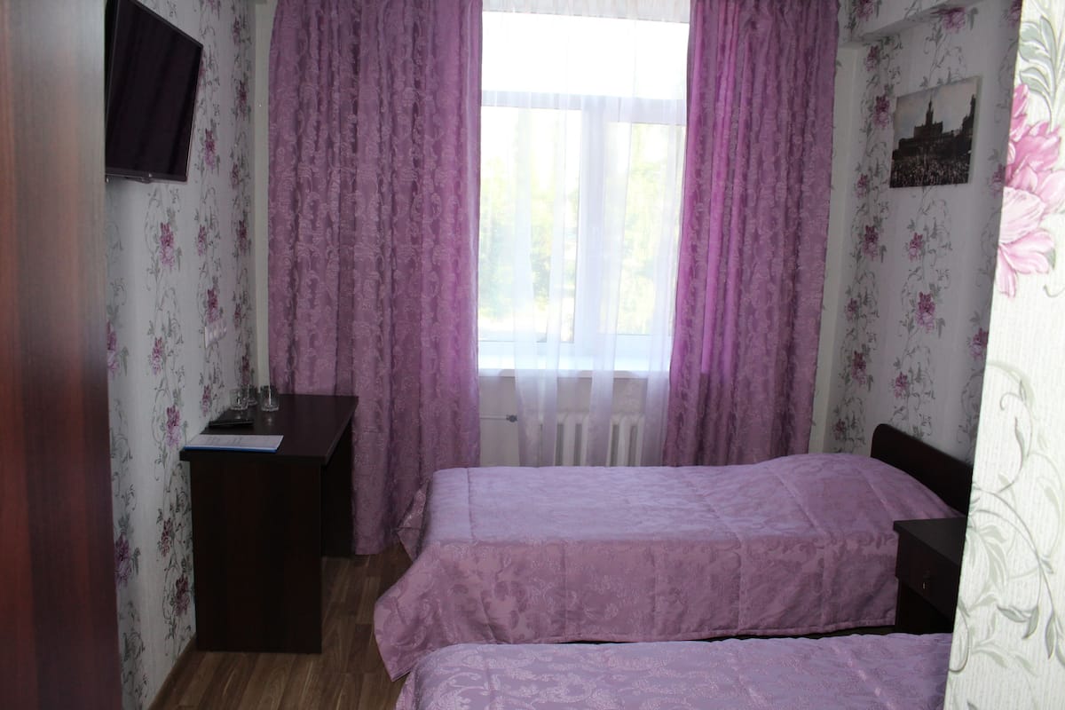 Un dormitorio con dos camas, un escritorio y una ventana con cortinas.