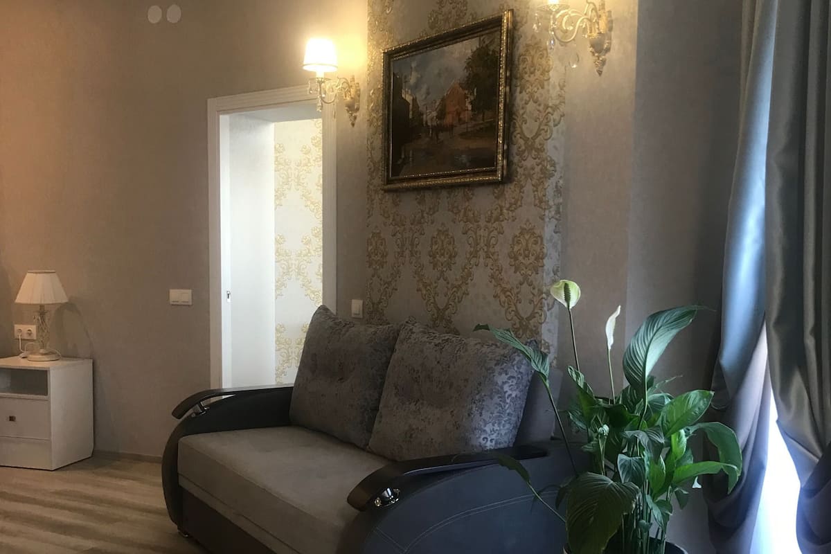 Una sala de estar moderna con un sofá, una planta en maceta y un cuadro en la pared.