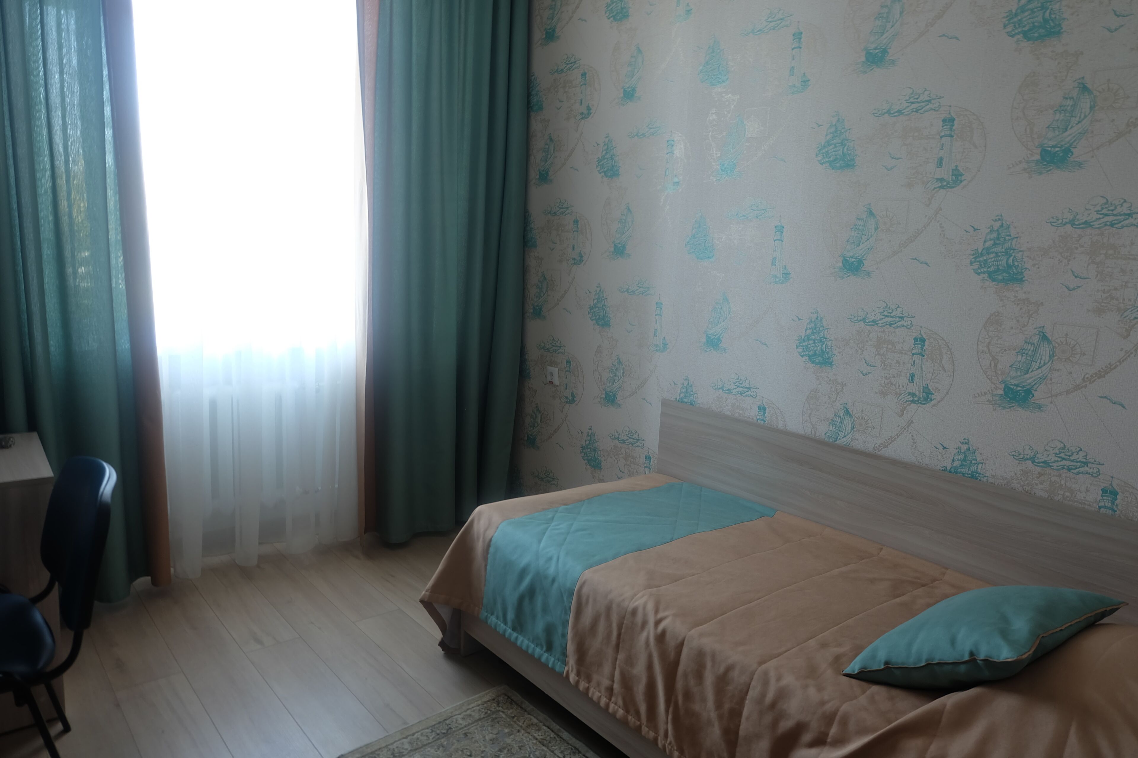 A bedroom with a bed, a desk, and a chair.
