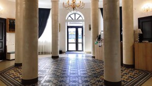 A grand hallway with large columns, a patterned floor, and a chandelier. - Hotel Bug Brest (Brest)