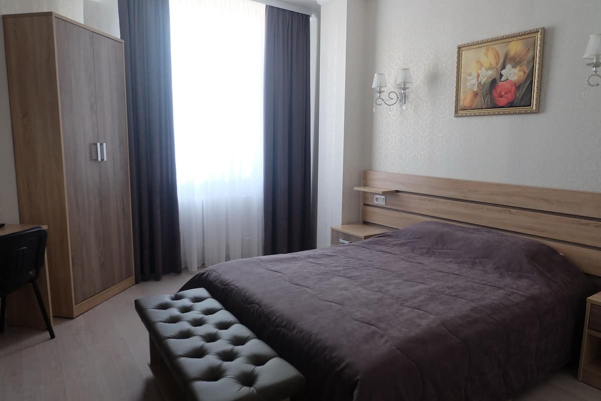 Un dormitorio con una cama grande, un armario de madera, un escritorio y un banco.