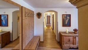 A hallway with wooden benches, a wooden cabinet, and framed artwork on the walls. - Gästehaus am Graben (Hoefen)