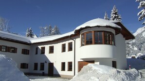 A white building with multiple windows and a curved corner section. - Gästehaus am Graben (Hoefen)