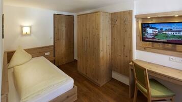 Un dormitorio con cama, armario de madera y escritorio con silla.