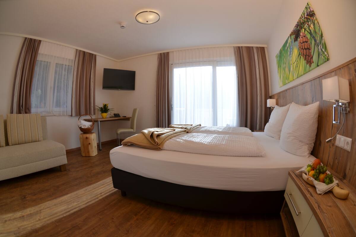 Una habitación de hotel con una cama grande, un escritorio, una silla, un televisor y un cuadro en la pared.