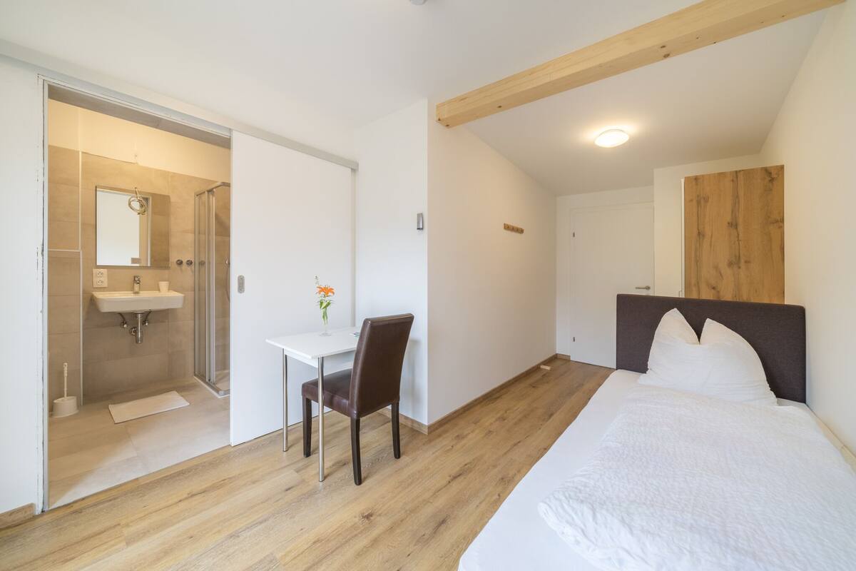 Un dormitorio con cama, escritorio y zona de ducha.