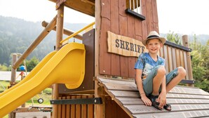 A wooden play structure with a slide and a sign that reads "SHERIFF". - Wellness Landhaus PARTH (Ossiach)
