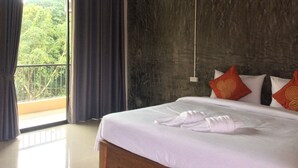 Habitación de hotel con cama, balcón y vistas a zonas verdes.