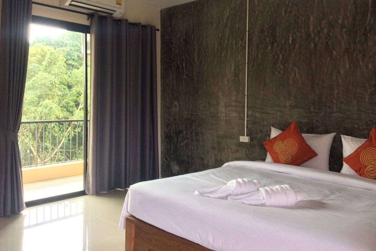 Habitación de hotel con cama, balcón y vistas a zonas verdes.
