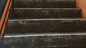 Una escalera con barandillas negras y escalones oscuros y con textura.