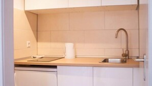 A compact kitchen with white cabinets, a sink, and a dishwasher. - Deluxe Studio 9 in der Stadt (Freiburg im Breisgau)