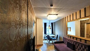 Un salon moderne avec un canapé, un coin repas comprenant une table et des chaises, et un grand miroir accroché au mur.