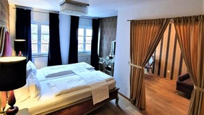 Une chambre d’hôtel avec un grand lit, un bureau avec une lampe, une chaise et une vue sur l’extérieur par la fenêtre.