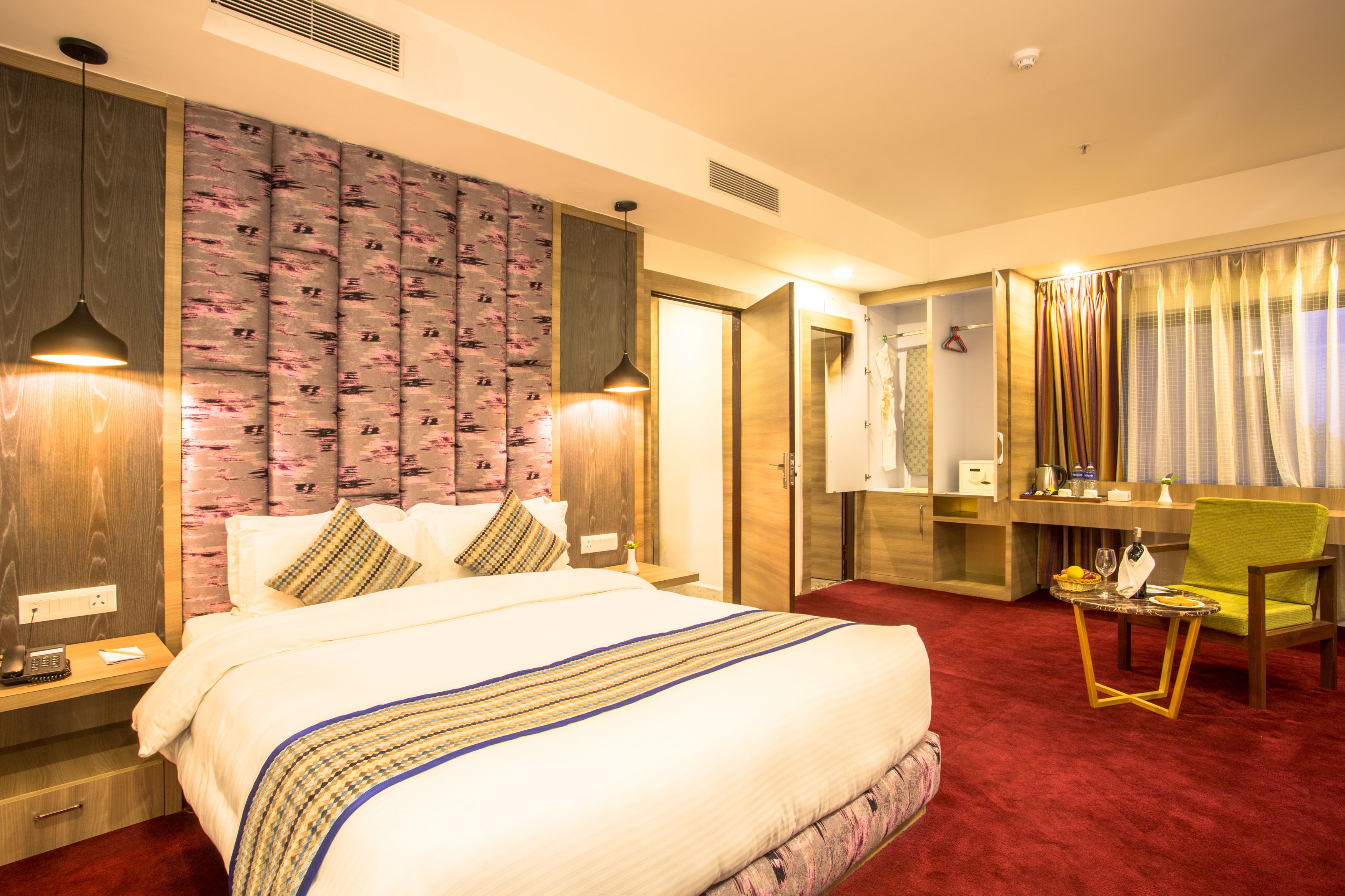A hotel room with a large bed, a desk, a chair, and a bathroom visible through an open door.