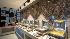 Ein Buffet mit mehreren Servierstationen und einer Wand aus Marmor im Hintergrund.