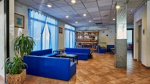 Un vestíbulo con asientos azules, una zona de bar y una planta grande en maceta.