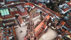 An aerial view of a historic town with a prominent Gothic church featuring a tall spire and intricate architecture. - Studio Rome in der Altstadt (Freiburg im Breisgau)