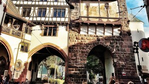 A historic building with a clock tower, a traditional half-timbered facade, and a stone archway. - Studio Rome in der Altstadt (Freiburg im Breisgau)