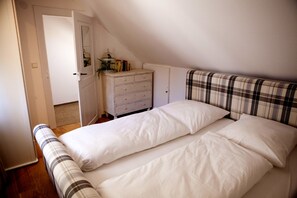 A bedroom with a bed, a dresser, and a door leading to another room. - New England Apartment (Freiburg im Breisgau)