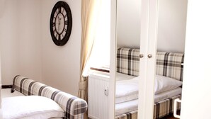 A bedroom with two beds, a wardrobe, a radiator, and a clock on the wall. - New England Apartment (Freiburg im Breisgau)