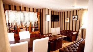 A living room with striped wallpaper, a leather sofa, a dining table with chairs, and a chandelier. - New England Apartment (Freiburg im Breisgau)