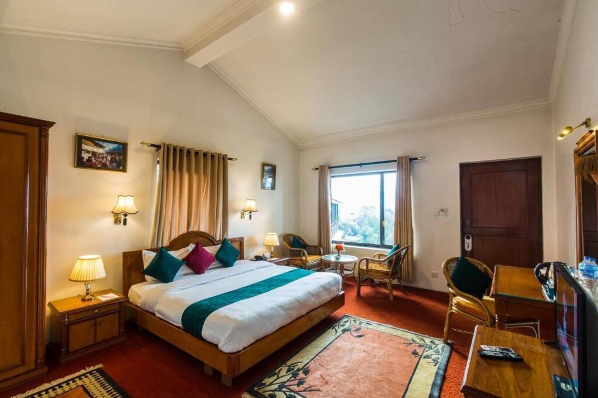 A hotel room with a large bed, bedside lamps, a desk, and a chair.