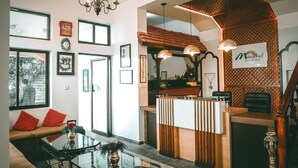A hotel lobby with a reception desk, a seating area with a sofa and a table, and framed pictures on the walls. - Mirabel Resort (Dhulikhel)